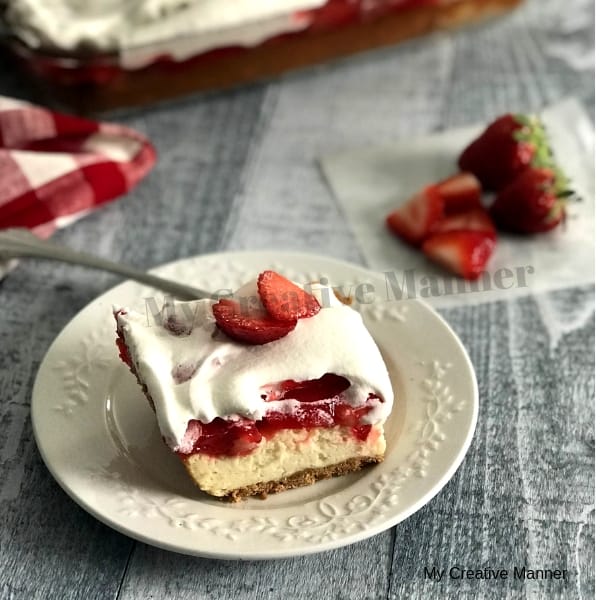 Strawberry Cheesecake Bars on a white plate with strawberries next to it.