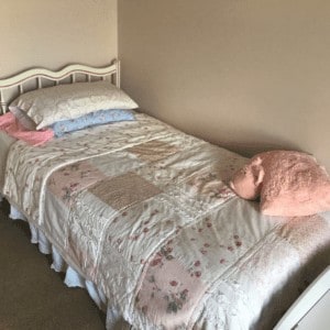 Shabby Chic bedding on a bed with a pink pillow.