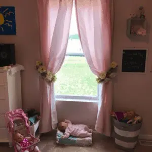 Pink curtains with toys in from of the window.