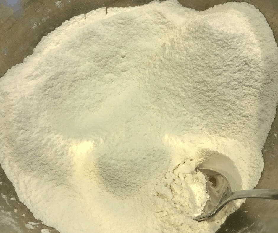 Flour in a metal bowl with a spoon. 