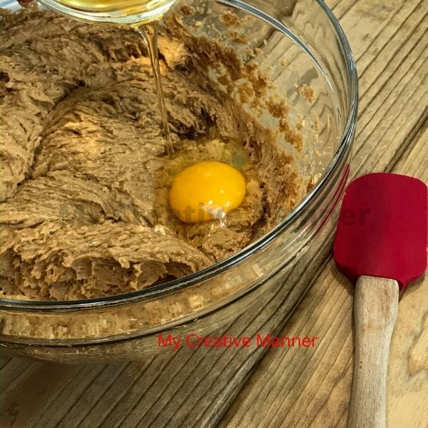 Eggs being added to a butter and brown sugar mixture for cookies.