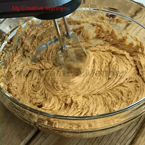 A hand mixer mixing the batter to Monster cookies.