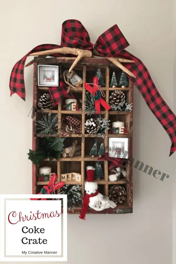 Antique Coke crate that is filled with many small Christmas decorations.