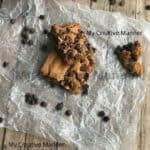 Three blonde brownies on wax paper with chocolate chips around them.