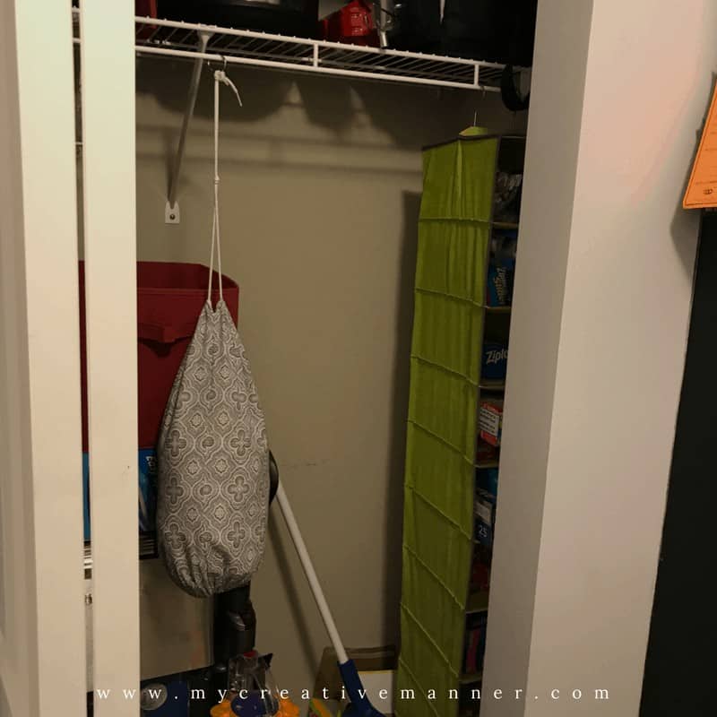 Inside a closet that has a green shoe bag hanging on a wire rack. 
