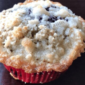 To die for blueberry muffin with crumb topping in a red liner.