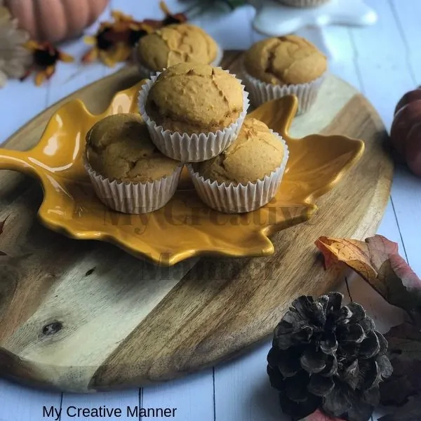 Wood tray with easy pumpkin muffins on it and leaves and a pumpkin around the wood tray.