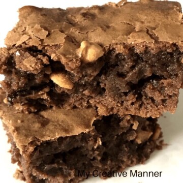 Two Resse's Peanut Butter Cup brownies stacked on top of each other on a white plate.