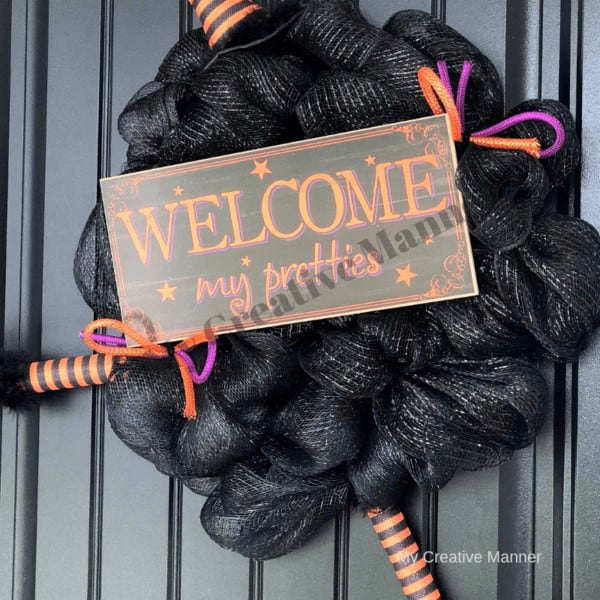 Witch wreath with sign that reads welcome my pretties. 