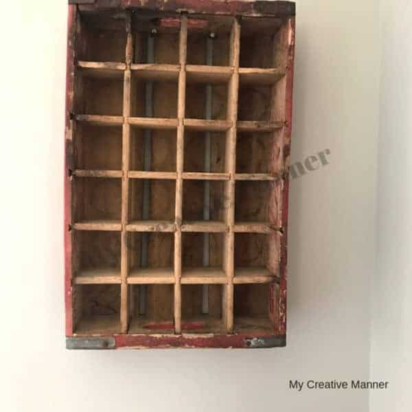 Empty Wooden Coke Crate that is hanging on a wall.
