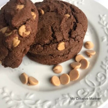white plate that has three chocolate peanut butter cookies and peanut butter chips on it.