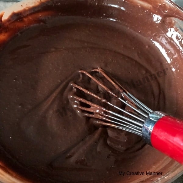 Chocolate pudding in a glass bowl with a whisk in the pudding. 