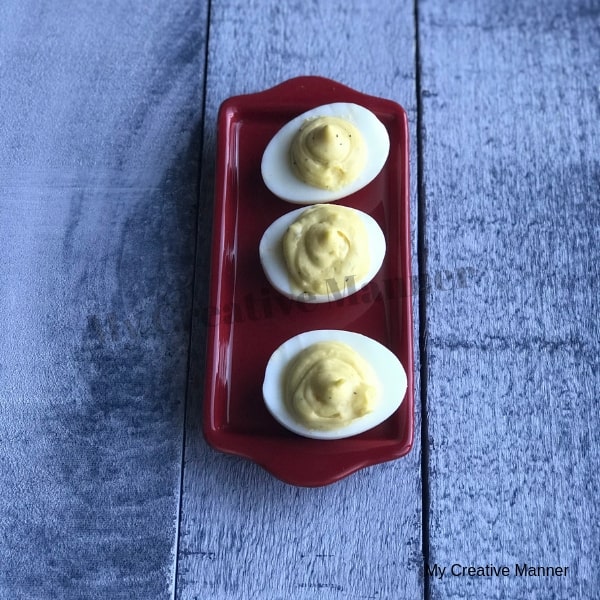 Three deviled eggs on a red plate.