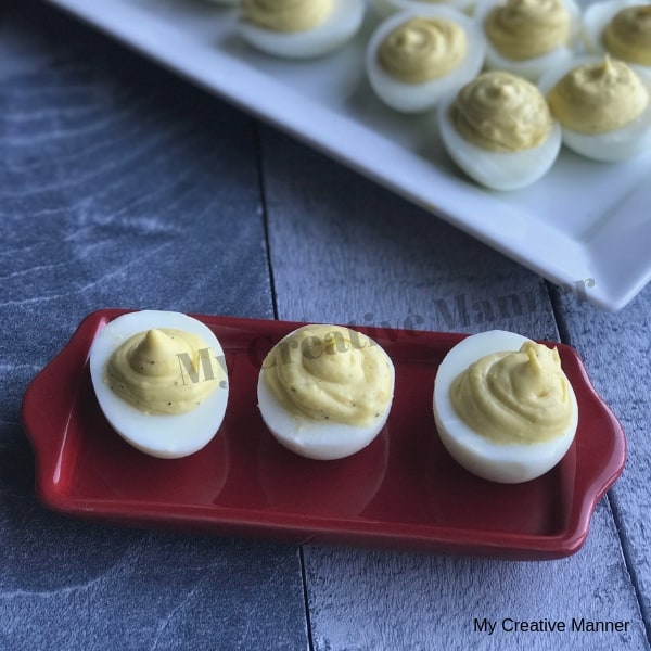red plate that holds three deviled eggs then a white plate that holds even more deviled eggs.