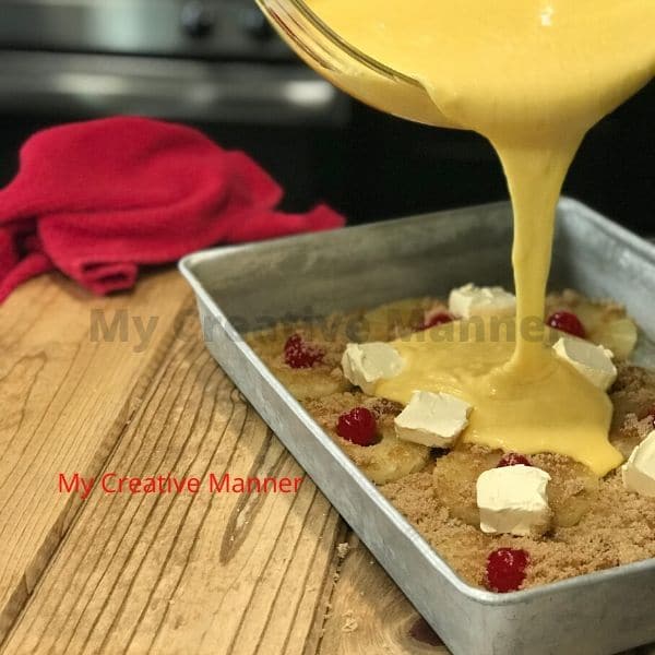 Cake mix batter being poured over top pineapple slices for a dessert recipe. 