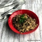 Red bowl filled with Hamburger Helper Beef Pasta with a grey and white napkin next to the bowl with a fork on the napkin.