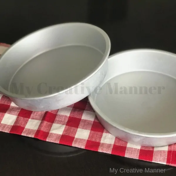 Two round cake pans sitting on a red and white napkin.