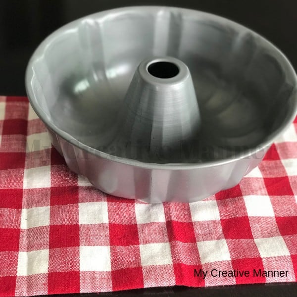 A metal bunt pan that is sitting on a red and white napkin.