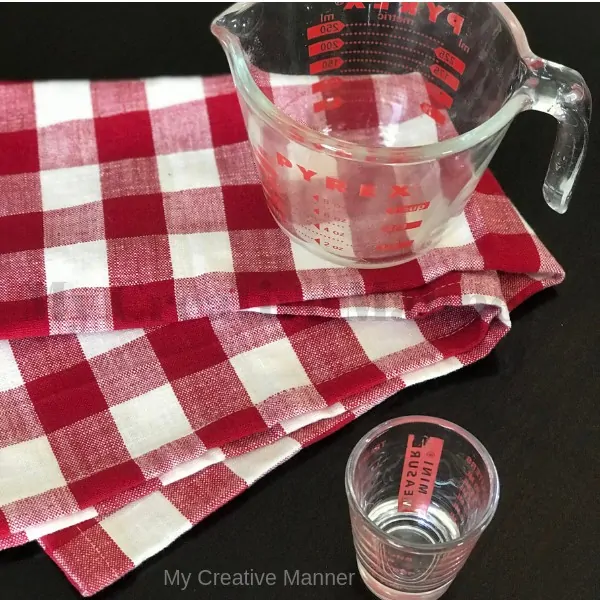 Liquid measuring cups sitting on a red and white napkin.