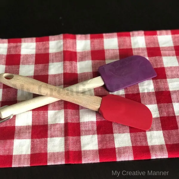 Two rubber spatulas sitting on a red and white napkin.