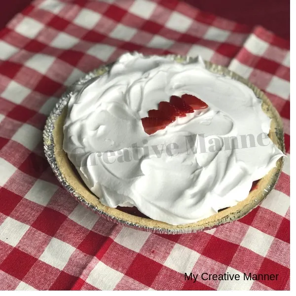 Full size strawberry pie sitting on a red and white napkin.