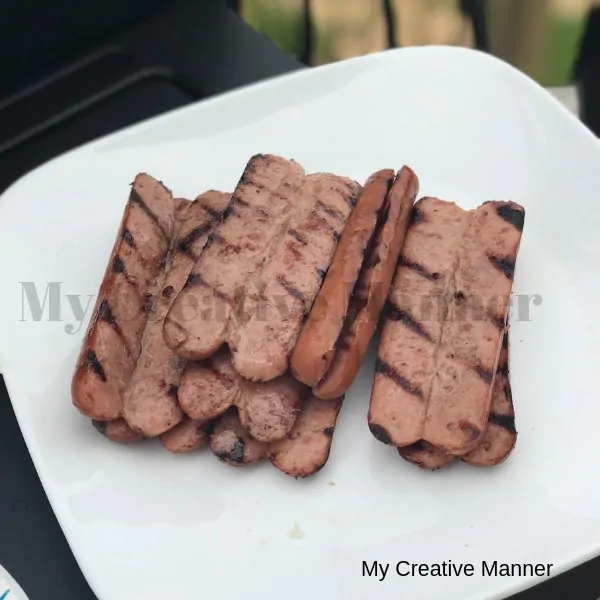 Grilled hot dogs on a while plate.