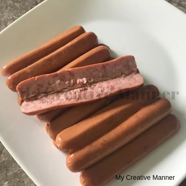 Sliced open hot dogs that are placed on a white plate.