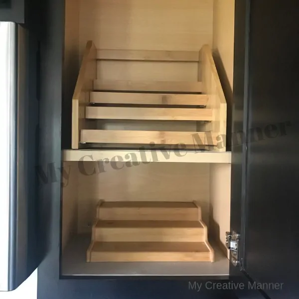 A cupboard that has two shelfs and each shelf has an empty spice rack on them.