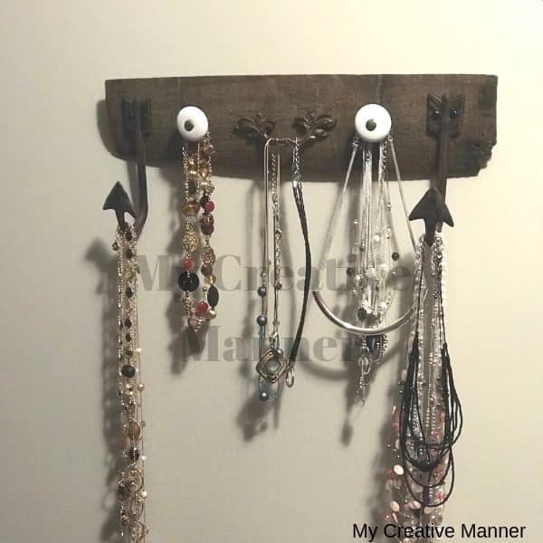 A board that has hooks on it and that is displaying necklaces.