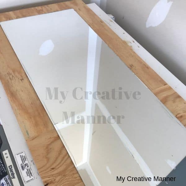 A cheap mirror being framed to a board.