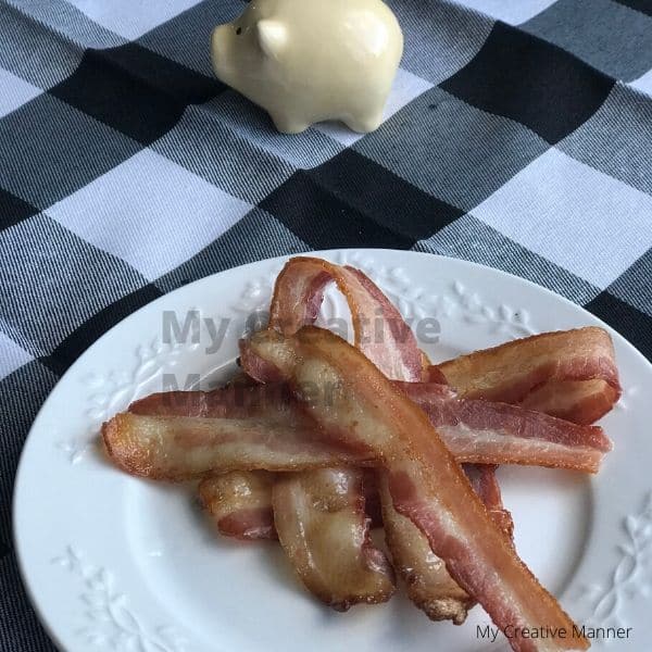 Bacon on a white plate that is on a black and white napkin.