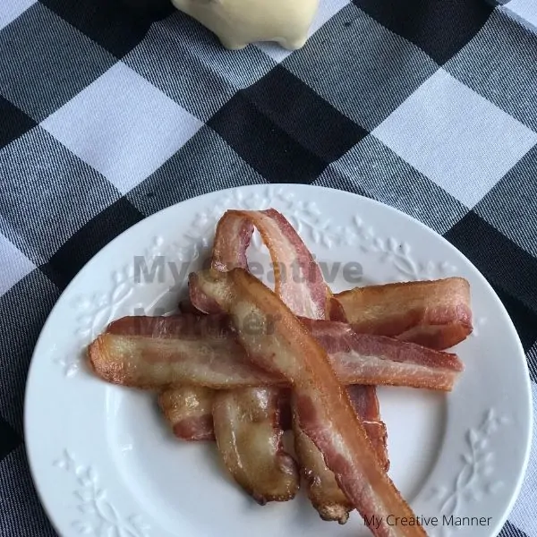 Bacon on a white plate that is on a black and white napkin.