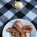 Bacon on a white plate that is on a black and white napkin.
