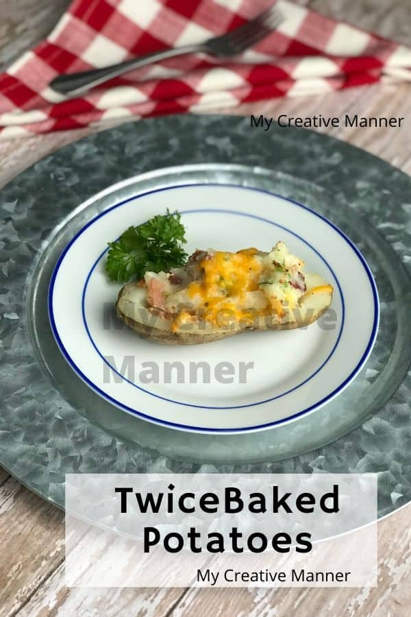 Red and white napkin behind a silver plate charger that has a white and blue plate on it. The plate has a twice baked potato with fresh parsley greens on the side. WIth the words Twice Baked Potatoes in a square box at the bottom of the page.