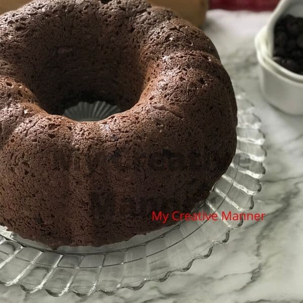 A full size chocolate bundt cake on a glass plate.