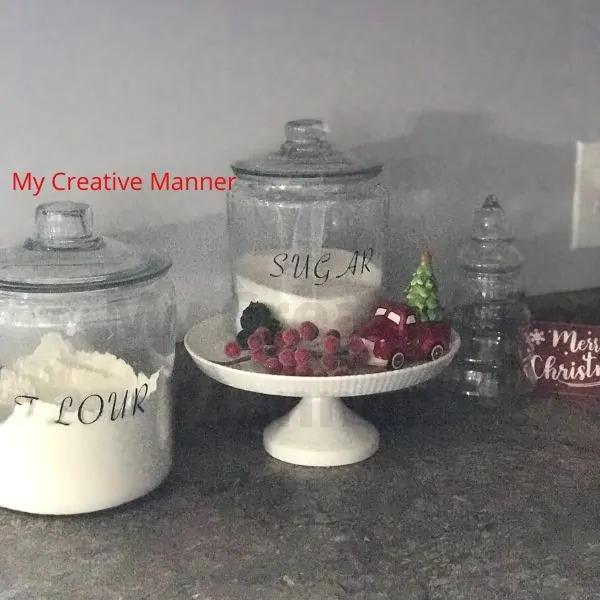 Four and sugar canisters that have Christmas decor around them.