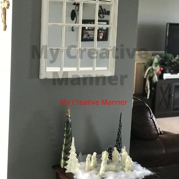 The nativity set on a table that is under a mirro.