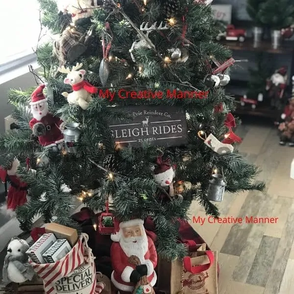 Rustic Christmas tree with a Santa and sled that has packages on it.