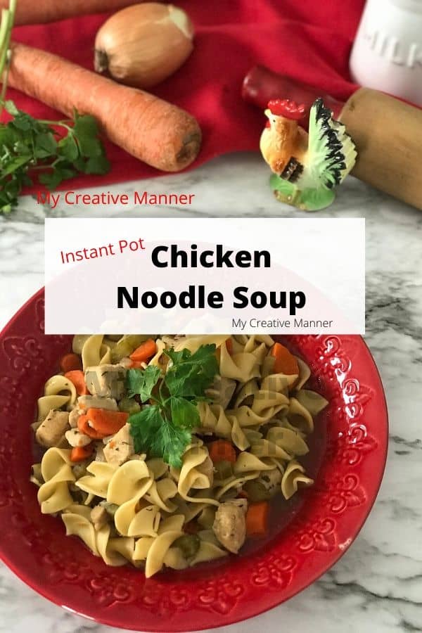 Red bowl filled with pressure cooker chicken noodle soup. In the background is a red towles, a carrot, fresh parsley, an onion, and a roaster figure. With a white box that has the words that says Instant Pot Chicken Noodle Soup.