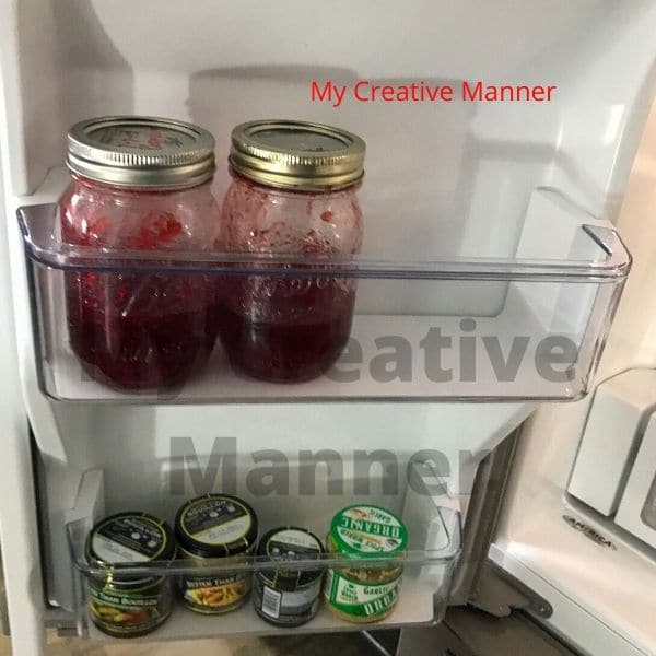 Homemade jam that is on the inside of a fridge door.