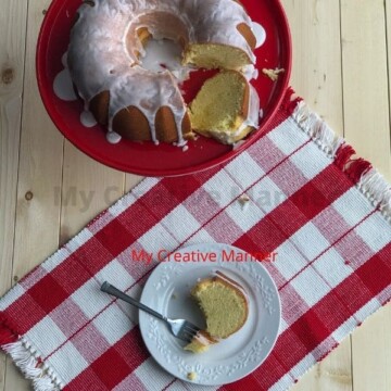 Lemon Cake on a cake stand and a piece on a plate.