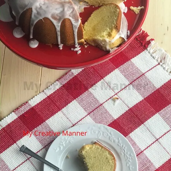 Cake on a cake stand and a piece on a white plate.