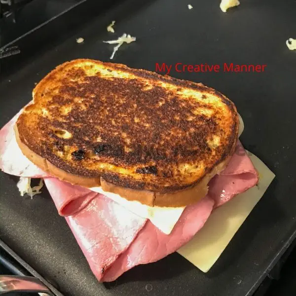 A grilled corned beef hero being cooked on a pan.