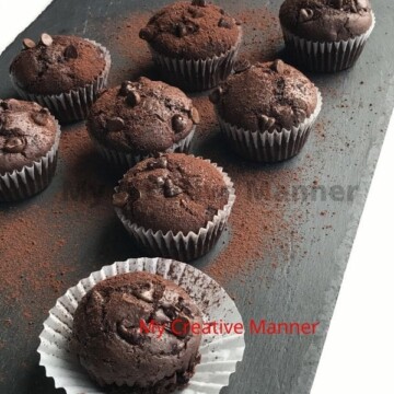 Double Chocolate Muffins on a platter that has been dusted with chocolate baking powder.
