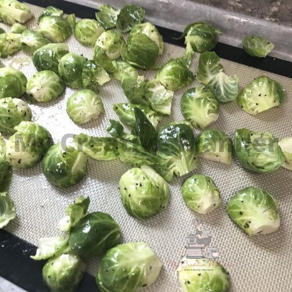 Sprouts coated in oil on a sheet pan.