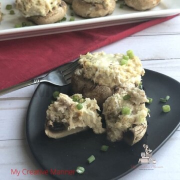 Crab Stuffed Mushrooms on a black plate with a fork.