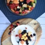 Honey lime rainbow fruit salad on a plate and in a large bowl.