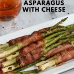 Prosciutto wrapped asparagus with cheese on a white platter.