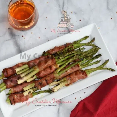 Grilled asparagus recipe on a white plate with a drink above it.