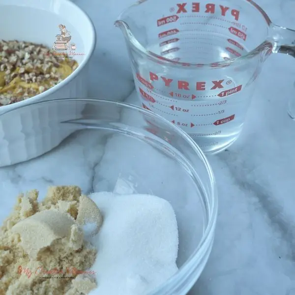 A bowl with white and brown sugar in it and a measuring cup with water in it.